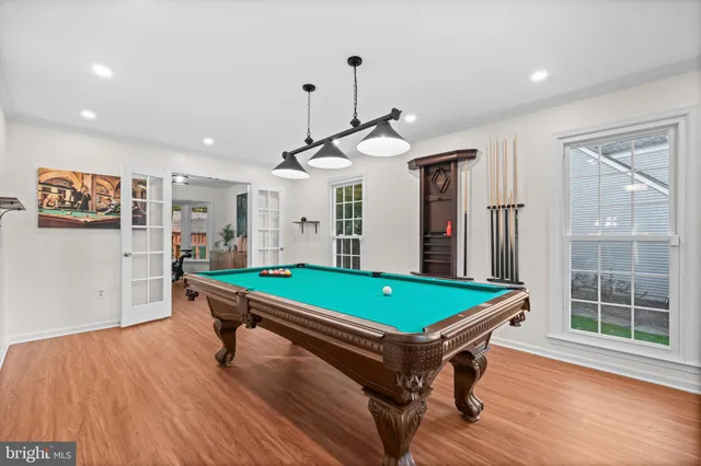 a room with pool table windows and wooden floor
