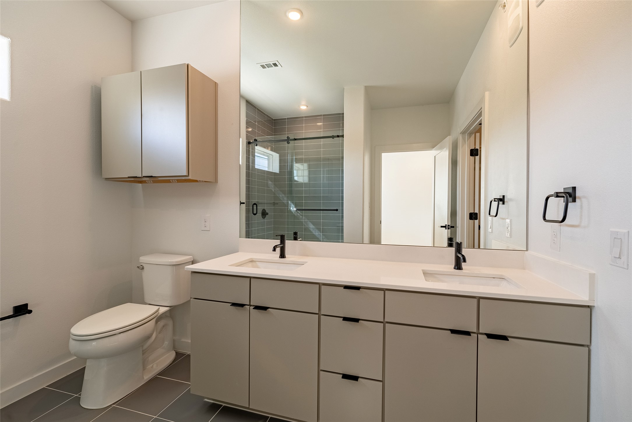 100 West Mockingbird Lane, Unit 201 Austin, TX 78745 - Photo 11 of 16 Bathroom with double vanity, dark tile patterned floors, and a stall shower