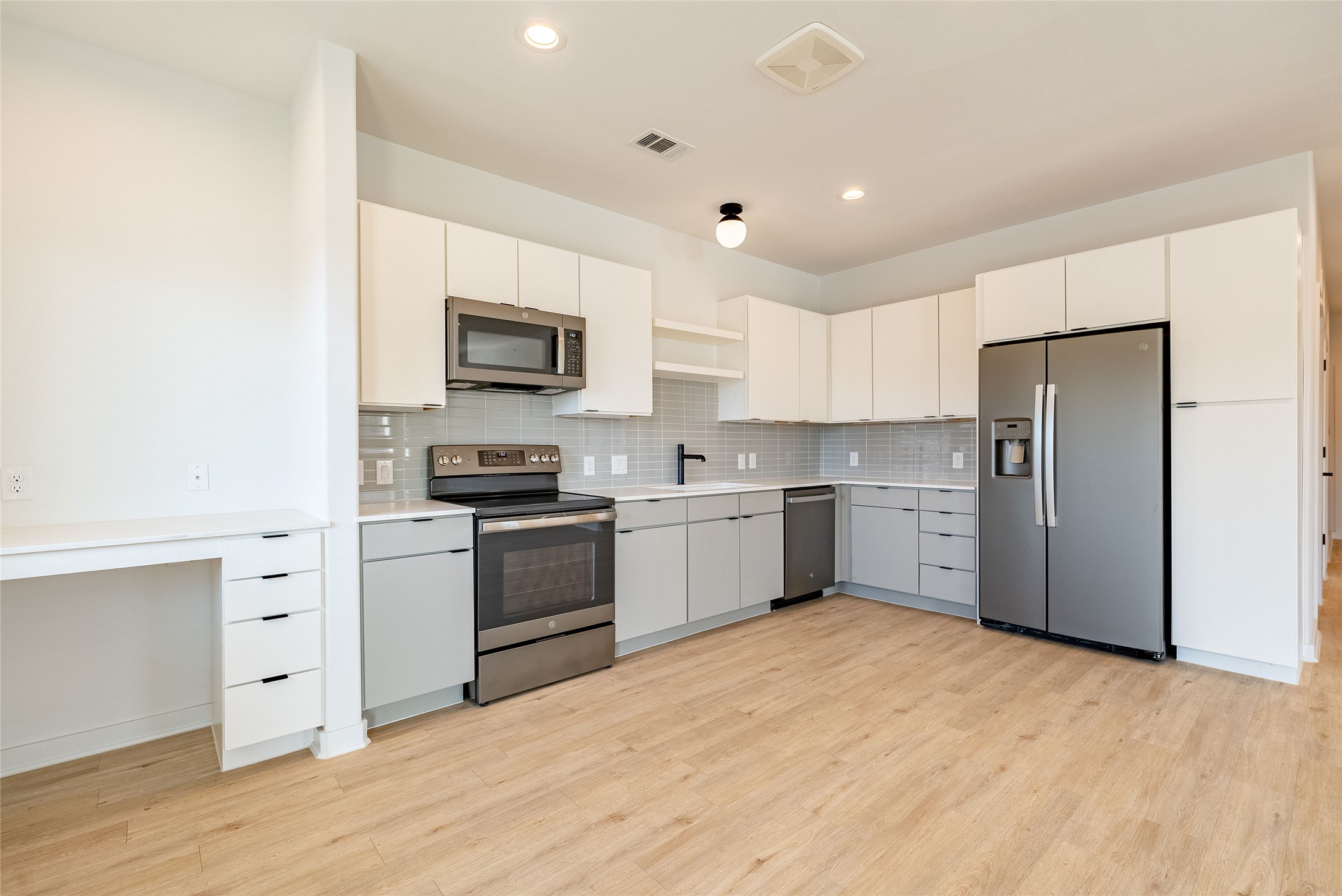 100 West Mockingbird Lane, Unit 201 Austin, TX 78745 - Photo 5 of 16 Kitchen featuring stainless steel appliances, open shelves, light wood-style floors, decorative backsplash, and white cabinets