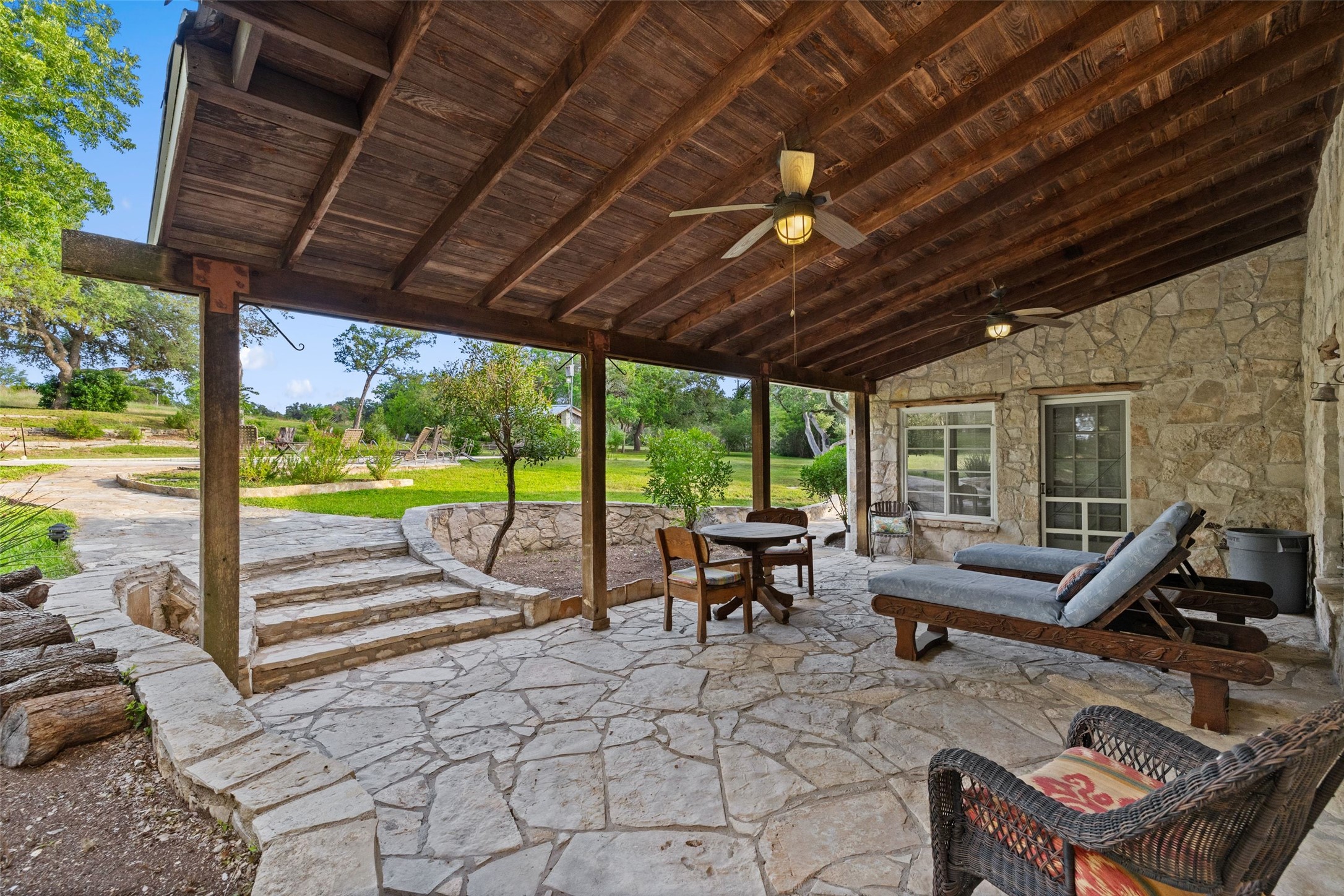 505 Red Corral Ranch Road Wimberley, TX 78676 - Photo 27 of 40 An inviting stone patio beneath a wooden beam ceiling, perfect for outdoor relaxation and entertaining.