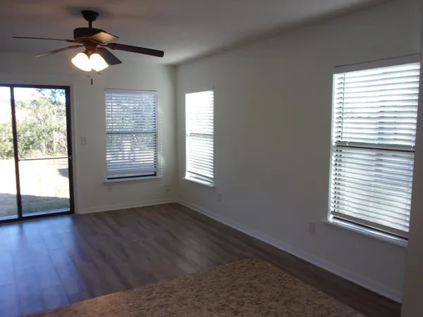 an empty room with wooden floor closet and windows