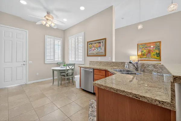 a living room with stainless steel appliances granite countertop furniture a fireplace a rug kitchen view and a window