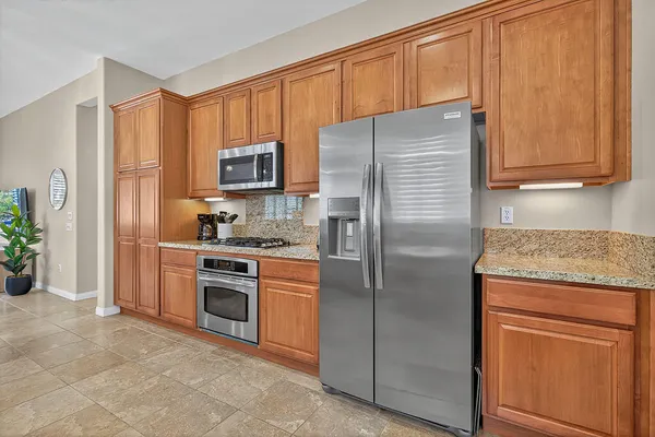 a kitchen with granite countertop a refrigerator stove and cabinets