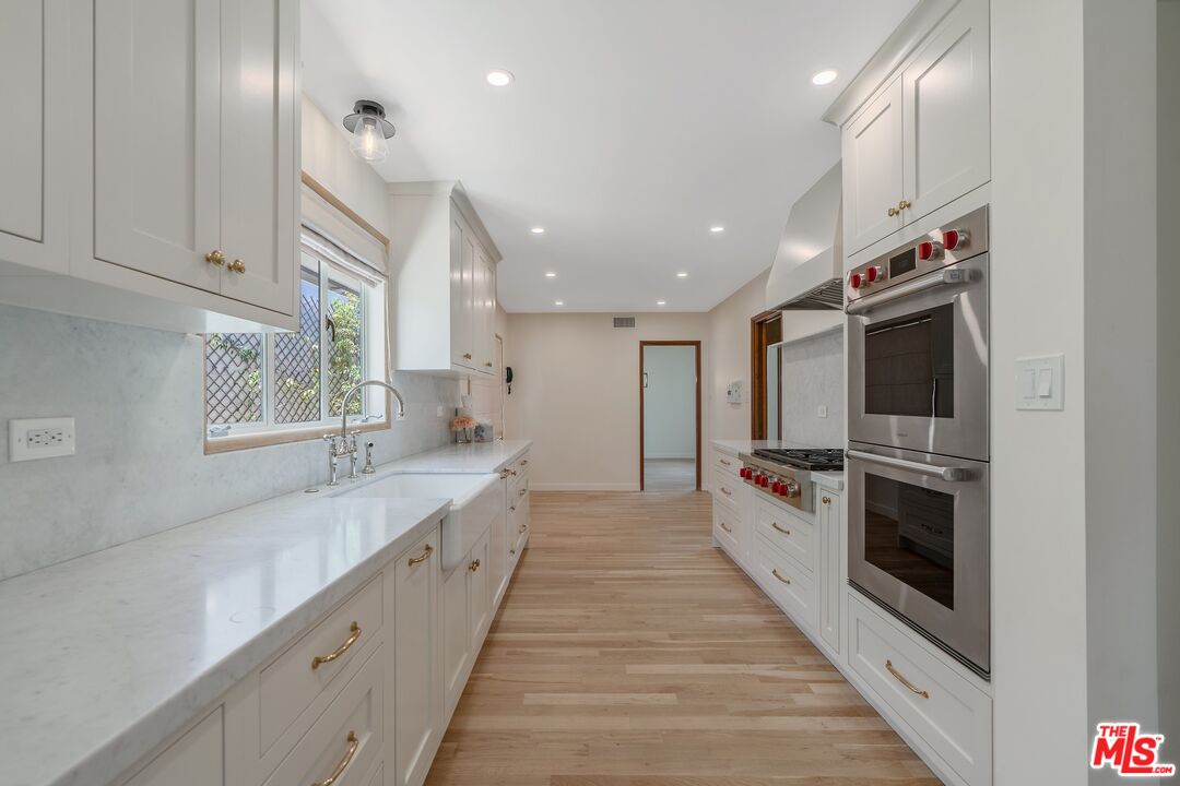 4245 Olympiad Drive View Park, CA 90043 - Photo 8 of 24 a large white kitchen with stainless steel appliances granite countertop a stove and a sink