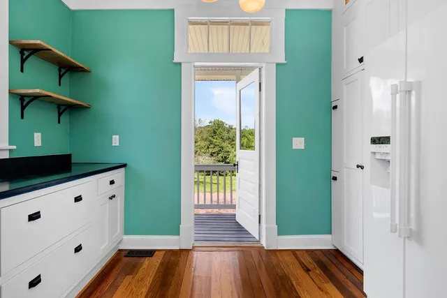 a view of an empty room with wooden floor fireplace and a window