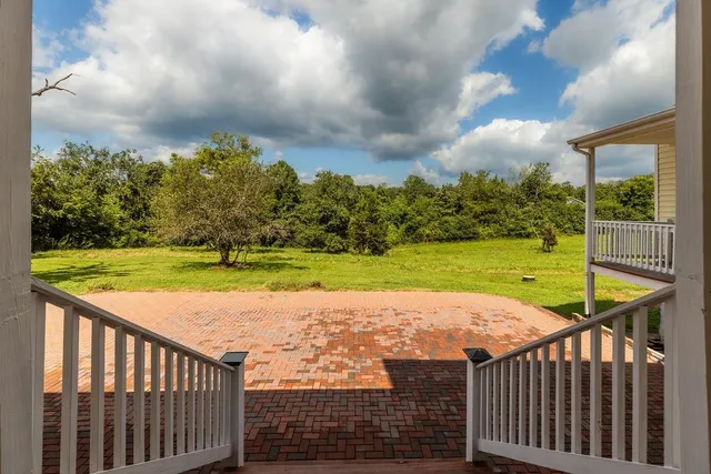 a view of an empty room with wooden floor fireplace and a window