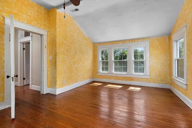 an empty room with windows and ceiling fan