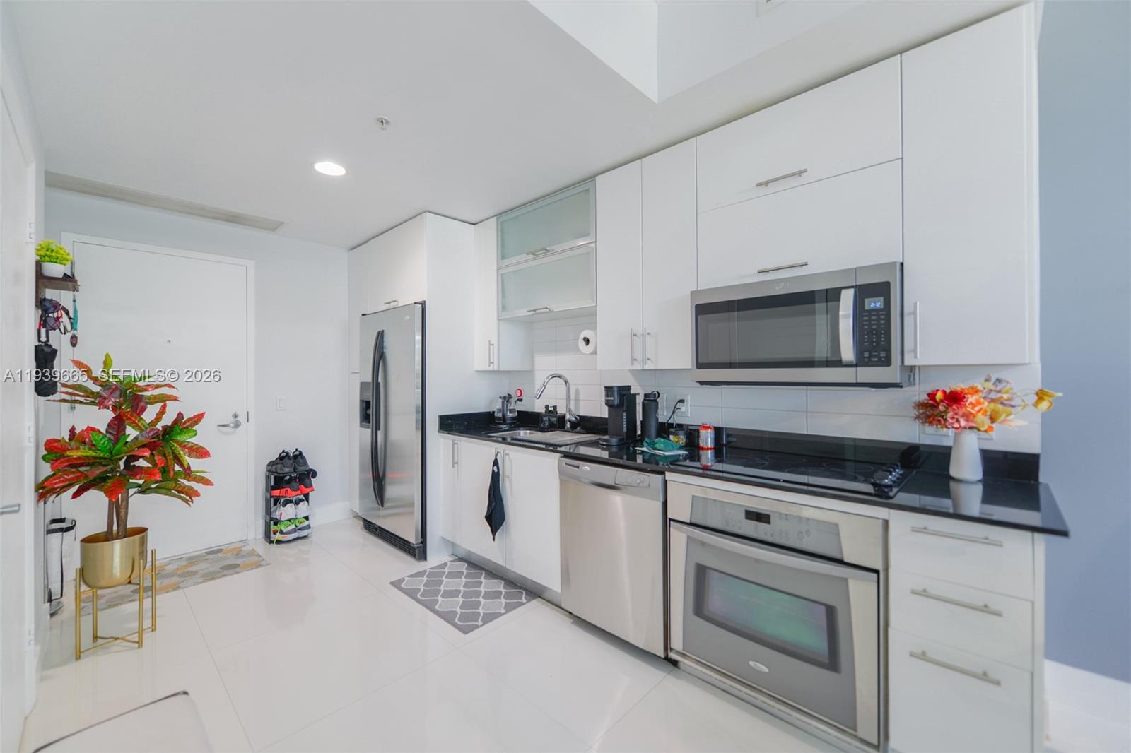 60 Southwest 13th Street, Unit 2404 Miami, FL 33130 - Photo 5 of 28 a kitchen with granite countertop white cabinets and stainless steel appliances