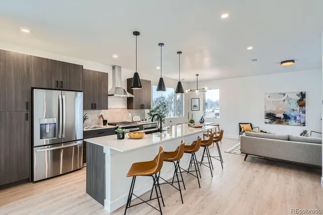 a kitchen with kitchen island a refrigerator a stove a dining table and chairs with wooden floor