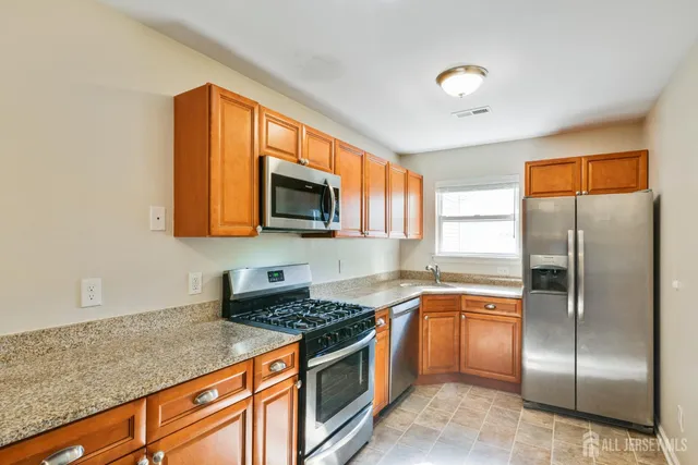a kitchen with stainless steel appliances granite countertop a stove a sink and a refrigerator