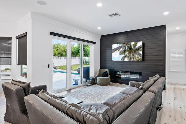 a living room with furniture a floor to ceiling window and a flat screen tv