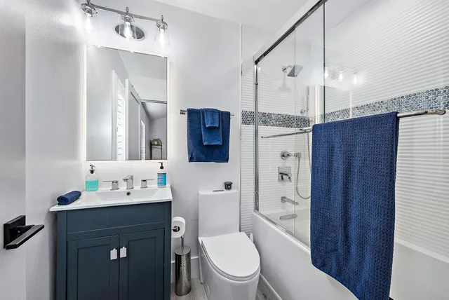 a bathroom with a sink a toilet a mirror a vanity and shower