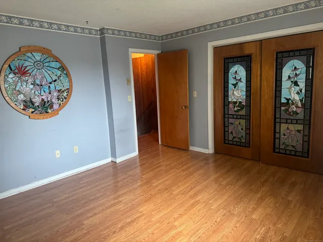 a view of an empty room with window and wooden floor