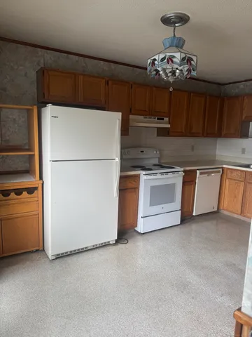 a kitchen with stainless steel appliances granite countertop a refrigerator a sink dishwasher a stove and a refrigerator