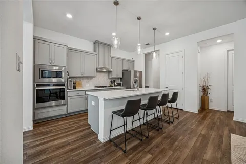 a kitchen with stainless steel appliances kitchen island granite countertop a table chairs refrigerator and sink