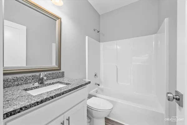 a bathroom with a granite countertop sink a toilet and a bathtub