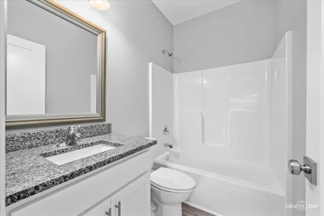 a bathroom with a granite countertop sink a toilet and a bathtub