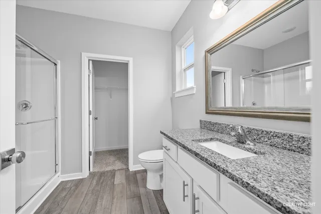 a bathroom with a granite countertop sink a toilet and shower