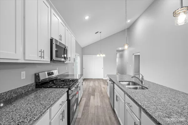 a kitchen with stainless steel appliances granite countertop a sink stove and cabinets