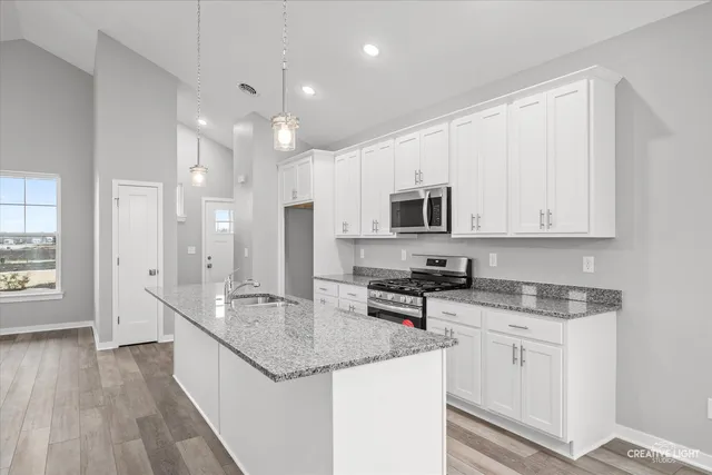 a kitchen with stainless steel appliances granite countertop a sink stove and cabinets
