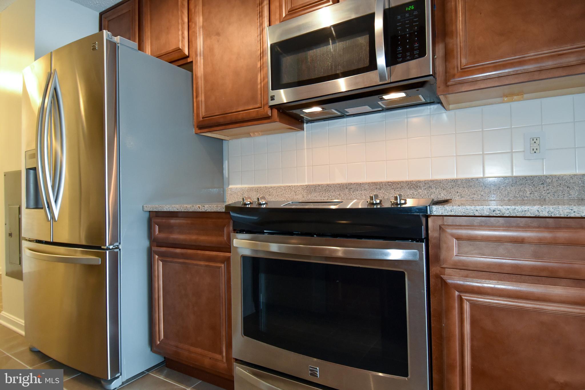 6101 Edsall Road, Unit 1706 Alexandria, VA 22304 - Photo 10 of 40 a kitchen with stainless steel appliances granite countertop a refrigerator stove and microwave