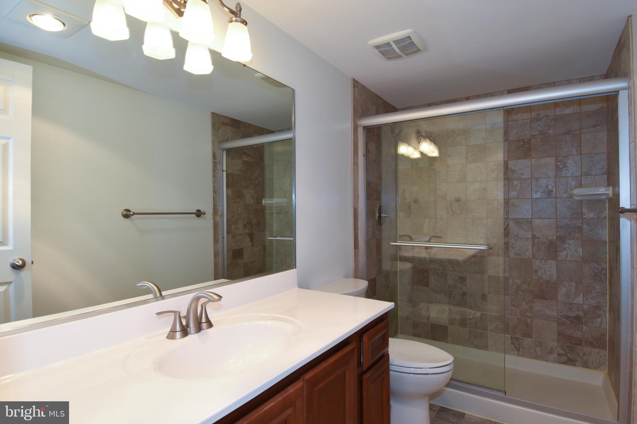 6101 Edsall Road, Unit 1706 Alexandria, VA 22304 - Photo 25 of 40 a bathroom with a sink a toilet a mirror and shower