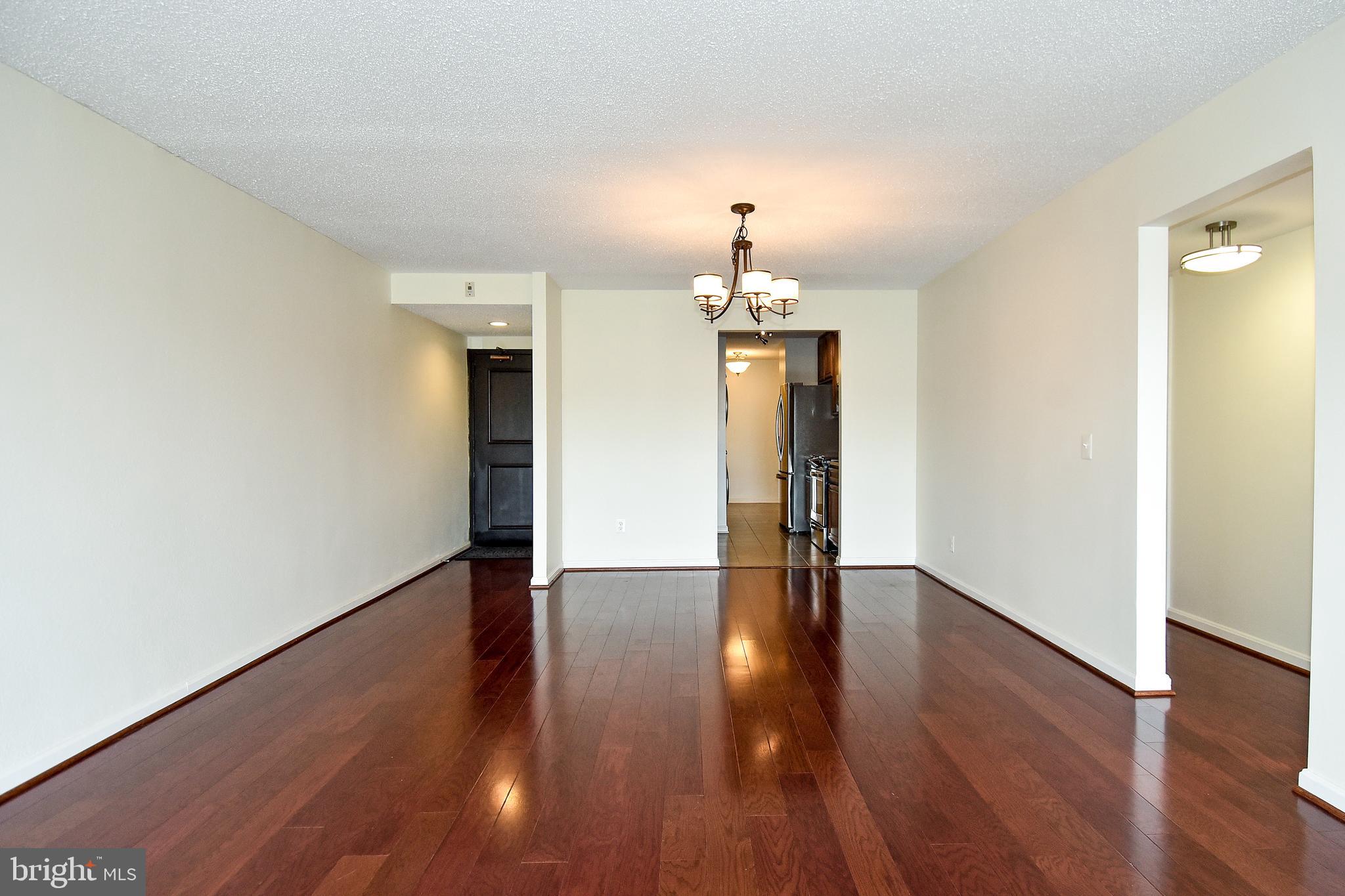 6101 Edsall Road, Unit 1706 Alexandria, VA 22304 - Photo 4 of 40 an empty room with wooden floor and chandelier