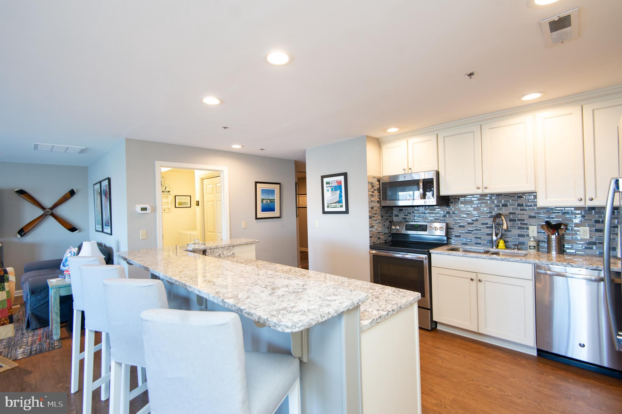 304 Academy Street, Unit 101 Cambridge, MD 21613 - Photo 16 of 56 a kitchen with stainless steel appliances kitchen island granite countertop a sink and cabinets