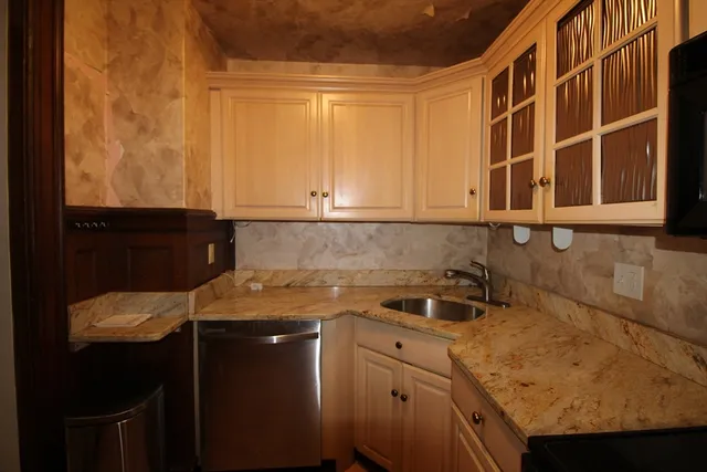 a view of a sink and dishwasher with wooden cabinet