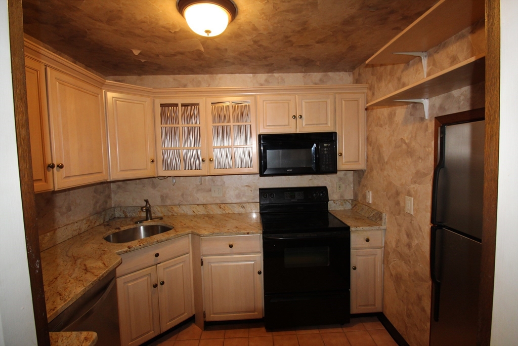 16 Balmoral Street, Unit 307 Andover, MA 01810 - Photo 6 of 10 a kitchen with stainless steel appliances granite countertop a refrigerator and a sink