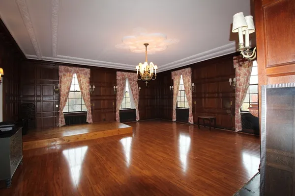 an empty room with wooden floor chandelier entryway and windows