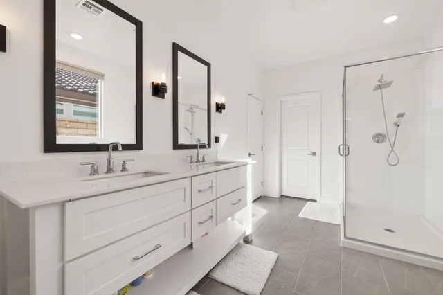 a spacious bathroom with double sink shower and a mirror