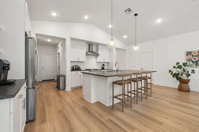 a kitchen with kitchen island stainless steel appliances a dining table chairs sink and stove