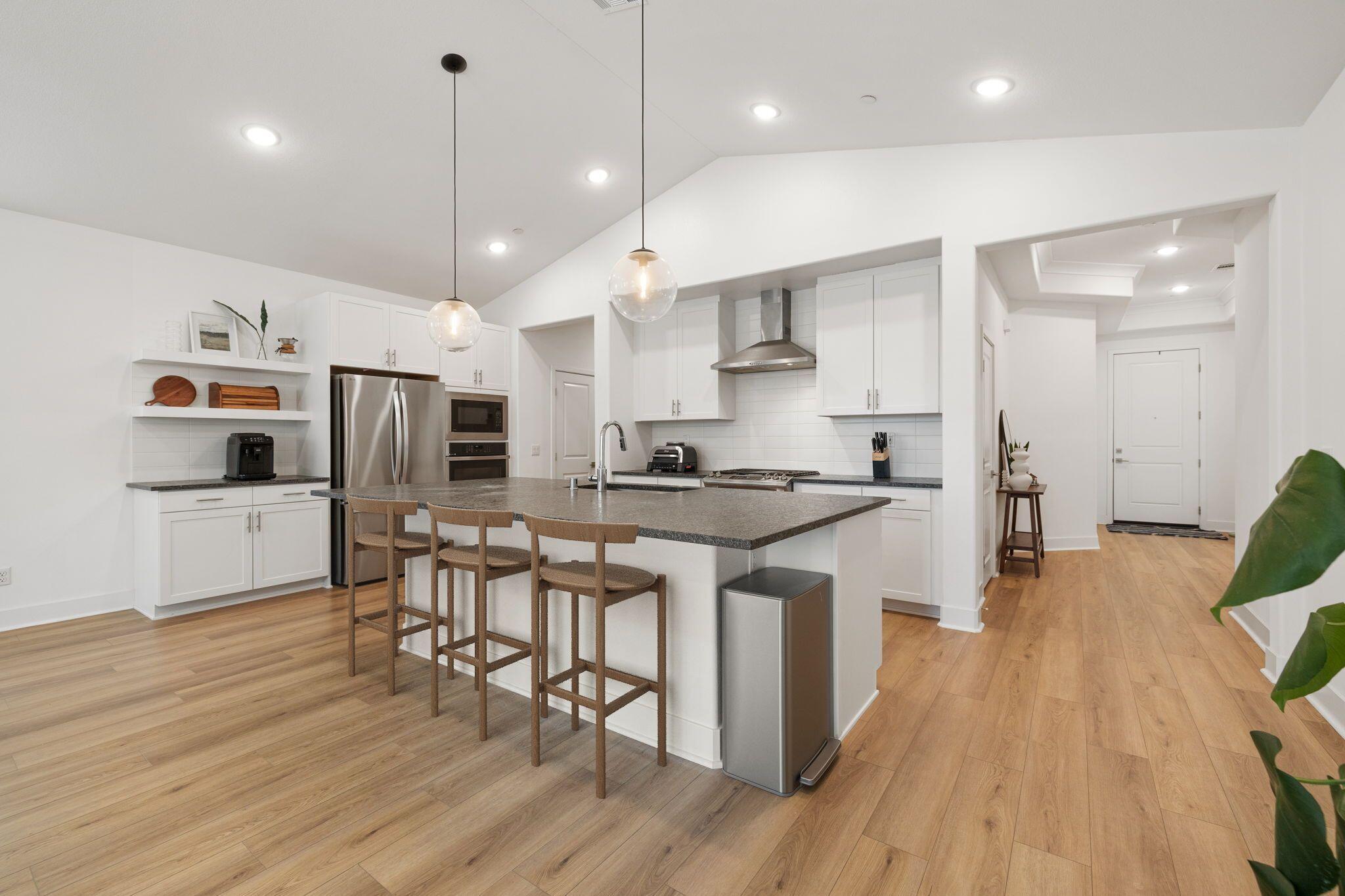 42501 Solicio Way Indio, CA 92203 - Photo 7 of 34 a kitchen with stainless steel appliances kitchen island granite countertop a table chairs refrigerator and microwave