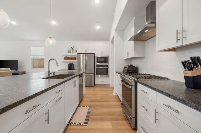 a kitchen with granite countertop a sink and white cabinets