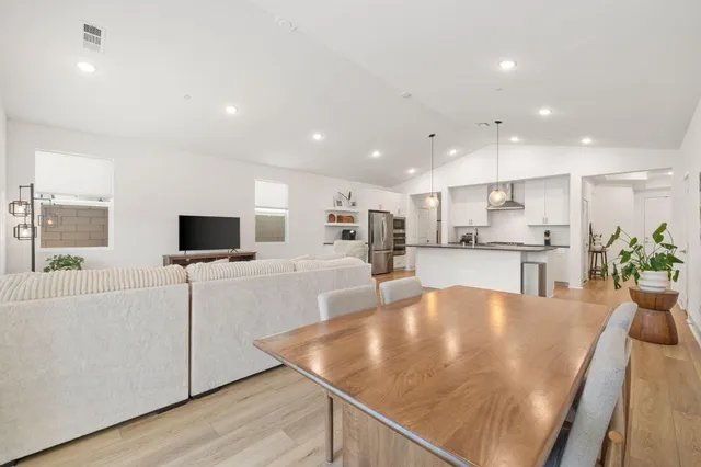 a kitchen with stainless steel appliances granite countertop a sink a stove a microwave a refrigerator a microwave oven and a dining table with wooden floor