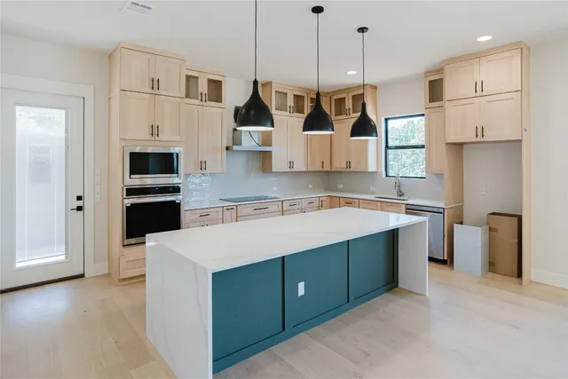 a view of kitchen with stainless steel appliances kitchen island wooden cabinets and a fireplace