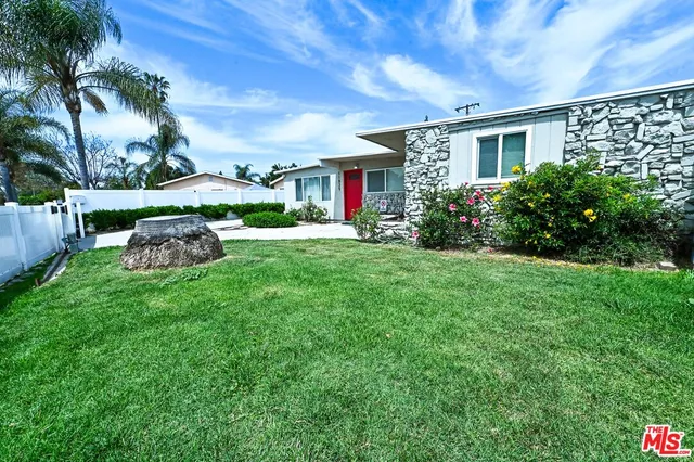 a front view of a house with a yard and potted plants