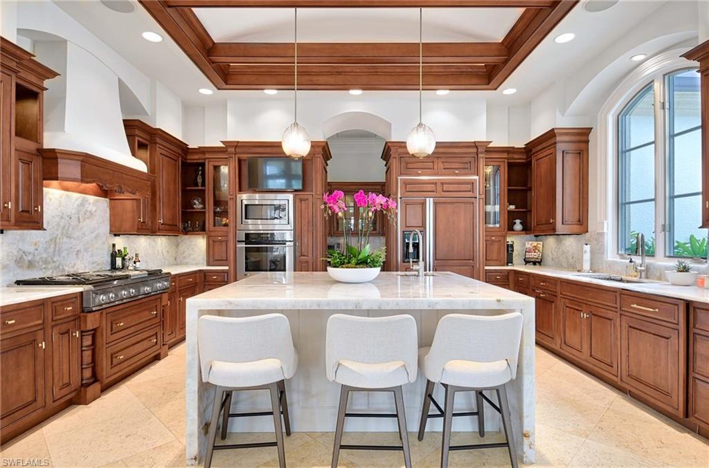 2390 Kingfish Road Naples, FL 34102 - Photo 11 of 37 a kitchen with stainless steel appliances granite countertop a stove a sink and a refrigerator