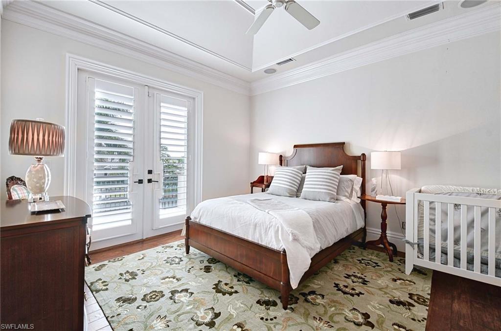 2390 Kingfish Road Naples, FL 34102 - Photo 24 of 37 a large bedroom with a bed and wooden floor