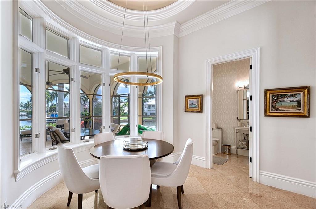 2390 Kingfish Road Naples, FL 34102 - Photo 8 of 37 a view of a dining room with furniture large windows and wooden floor