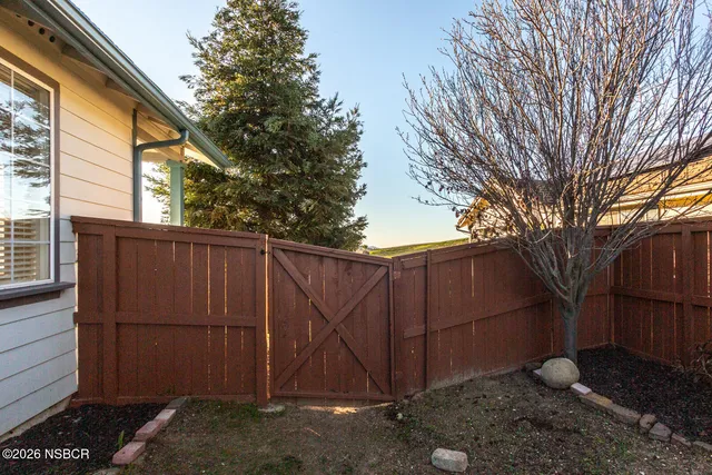 a view of backyard with large tree and wooden fence