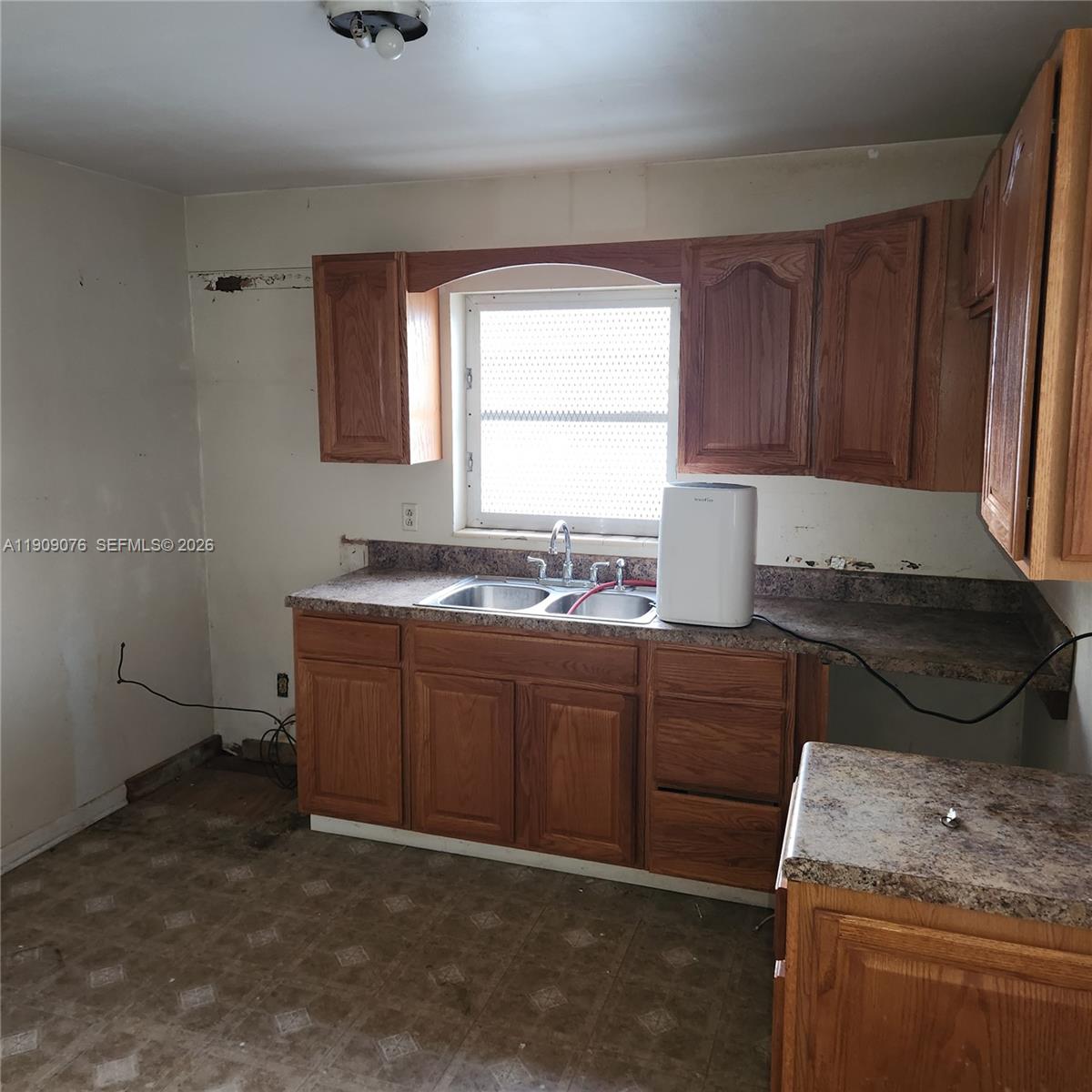 1547 West 10th Street Riviera Beach, FL 33404 - Photo 9 of 20 a kitchen with granite countertop a sink a stove and a wooden cabinets
