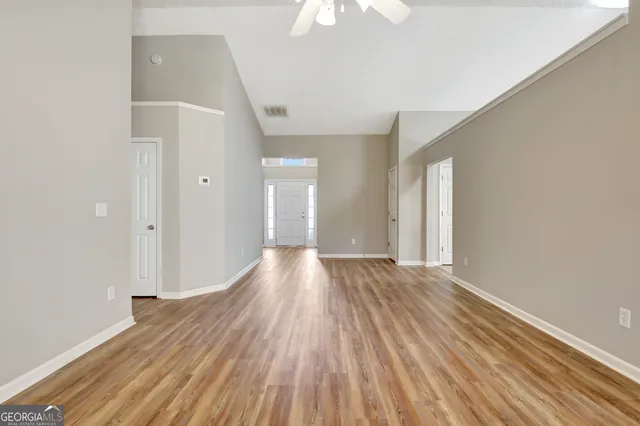 a view of an empty room with wooden floor and a window