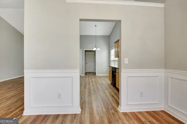 a kitchen with granite countertop a refrigerator a sink dishwasher a stove and white cabinets with wooden floor