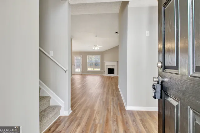 an empty room with wooden floor a fireplace and windows