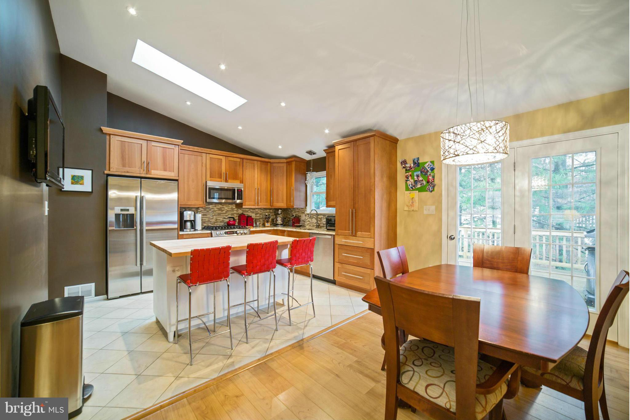 a dining room with stainless steel appliances a dining table chairs and a refrigerator