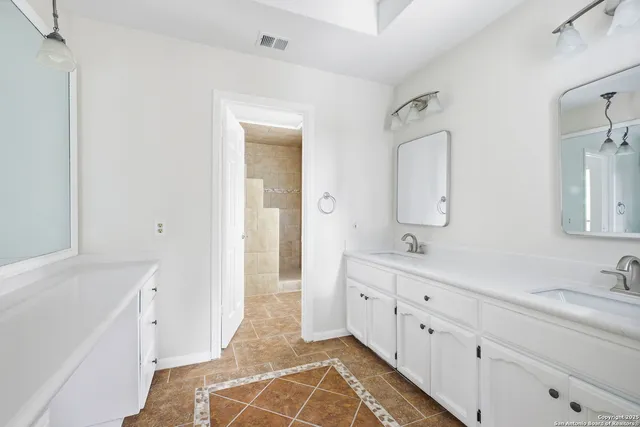 a spacious bathroom with double vanity sink a mirror and a shower