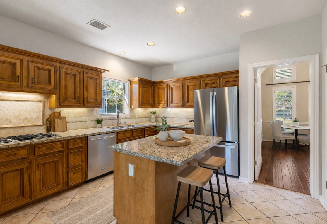 25722 Overlake Drive Spring, TX 77380 - Photo 16 of 50 This kitchen features warm, raised wooden cabinets (real wood!!), granite countertops, a central island with seating, an updated stainless steel dishwasher, a newer stainless steel refrigerator that is conveyed, and ample lighting, creating a cozy and functional space.