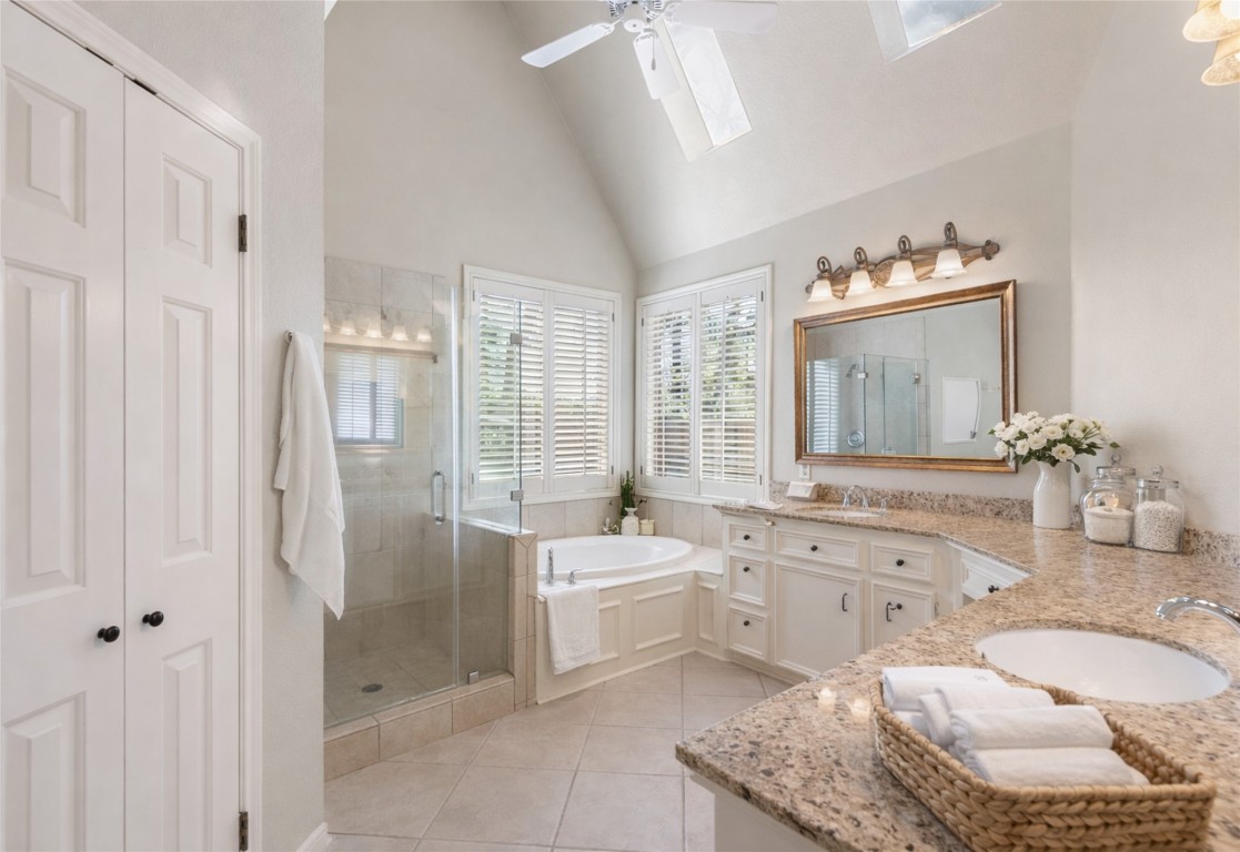 25722 Overlake Drive Spring, TX 77380 - Photo 27 of 50 The primary ensuite bathroom features double sinks, a huge vanity, framed mirrors, a spacious glass-enclosed shower, a tiled bathtub, and large windows with plantation shutters flooding the room natural light.